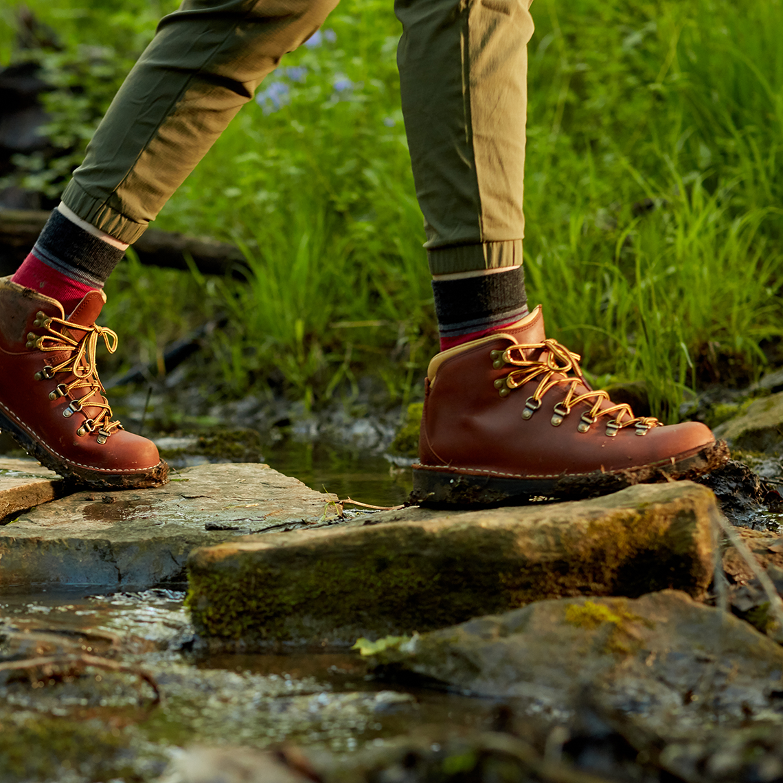 Closeup of hikers crossing a stream on stepping stones