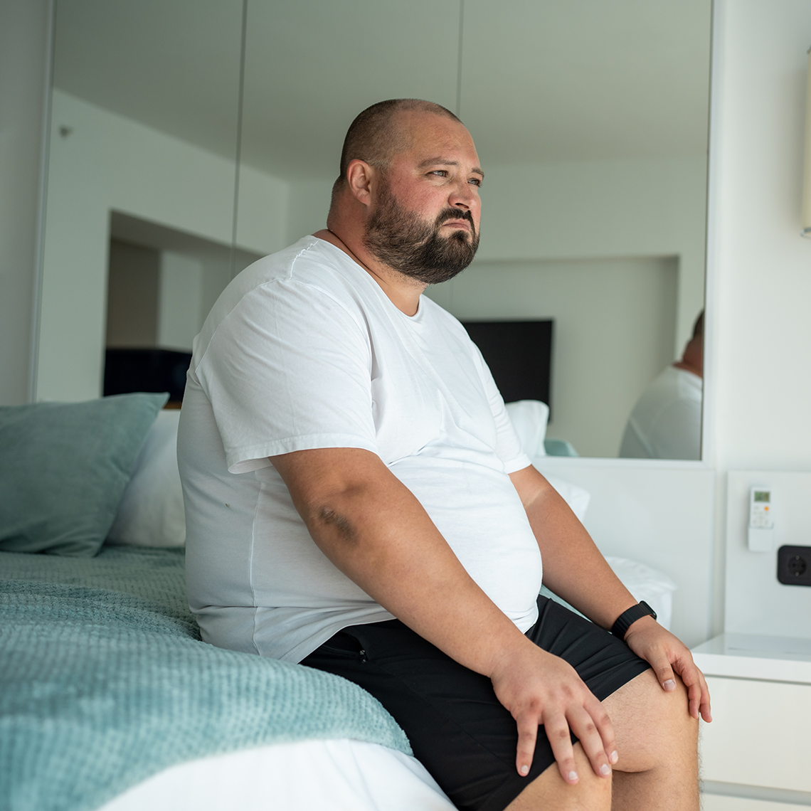 Obese man sitting on a bed