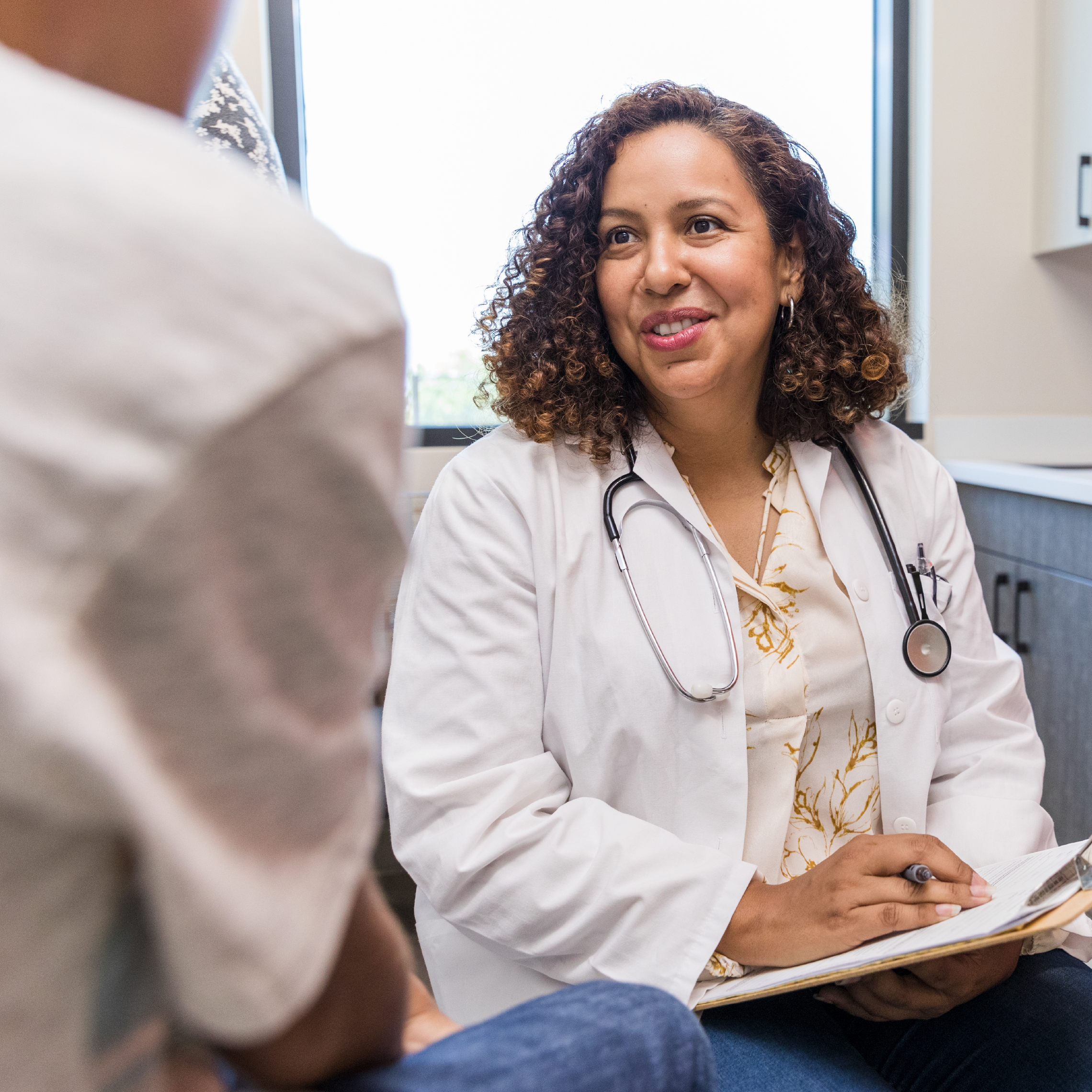 A physician in an exam room talking with a patient