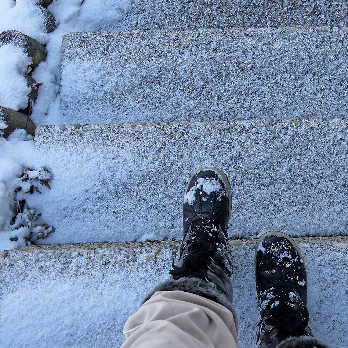 A person about to descend an icy set of stairs